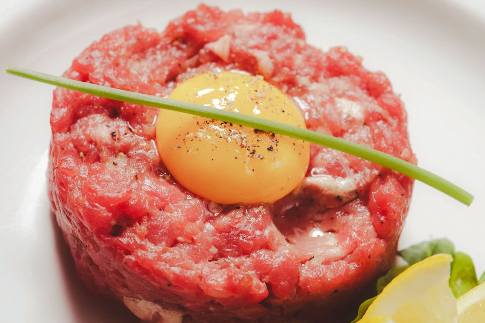 A dish of freshly prepared steak tartare with a raw egg yolk on top, a delicacy in French cuisine.