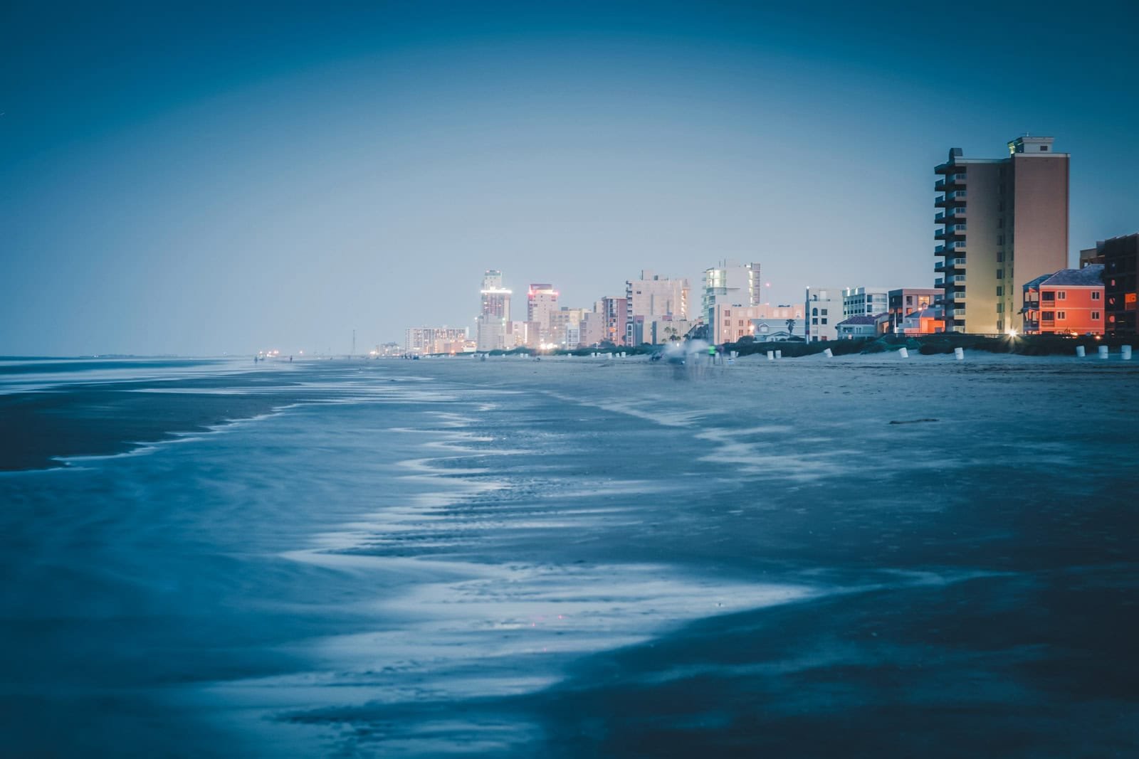 A wide, quiet beach with sand dunes on South Padre Island, a warm place to visit in December in the USA.